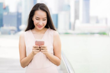 Asyalı kadın konuşmak veya metin için akıllı telefon veya cep telefonu kullanarak