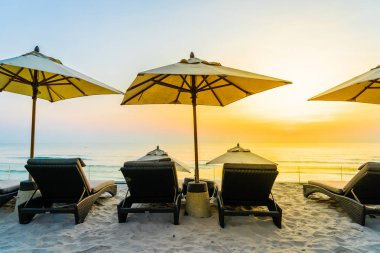 Şemsiye ve şezlong üzerinde güzel plaj ve gündoğumu zaman seyahat ve tatil için deniz