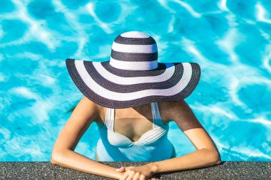 Seyahat ve tatil kavramı için yüzme havuzunda şapkalı güzel genç Asyalı kadın