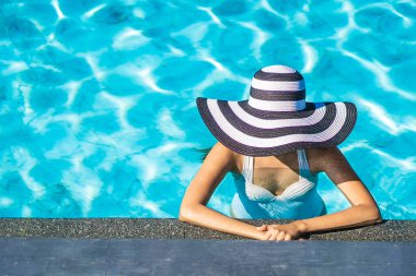 Seyahat ve tatil kavramı için yüzme havuzunda şapkalı güzel genç Asyalı kadın