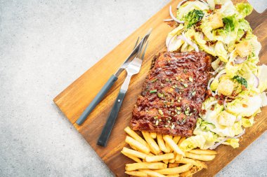 Izgara Barbekü domuz eti ripleri ahşap plaka üzerinde sebze ve patates kızartması ile