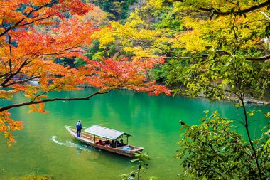 Akçaağaç ağaç yaprak ve etrafında tekne ile güzel Arashiyama Nehri 