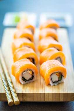 Somon Balık et suşi roll maki ahşap plaka üzerinde