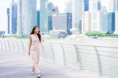 Asyalı kadın konuşmak veya metin için akıllı telefon veya cep telefonu kullanarak