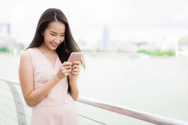 Asyalı kadın konuşmak veya metin için akıllı telefon veya cep telefonu kullanarak — Stok fotoğraf