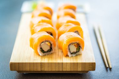 Somon Balık et suşi roll maki wasabi ve soya sosu - Japon yemekleri tarzı ahşap plaka üzerinde