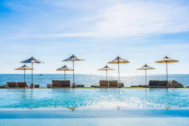 Deniz okyanus üzerinde sky şemsiye ve lüks Açık Yüzme havuzunda hotel resort tatil seyahat ve tatil için çevresinde sandalye ile güzel manzara