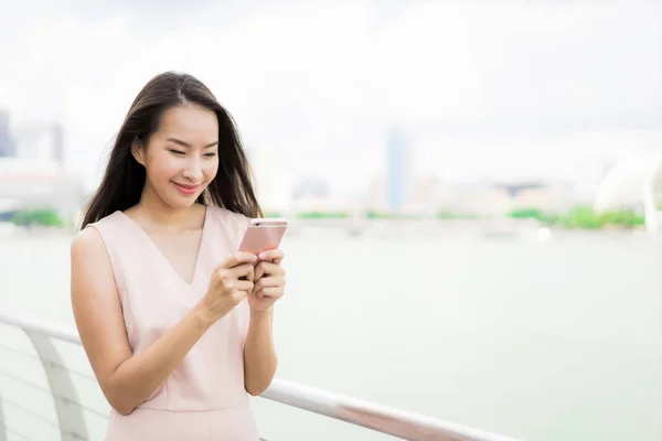 Asyalı kadın konuşmak veya metin için akıllı telefon veya cep telefonu kullanarak — Stok fotoğraf