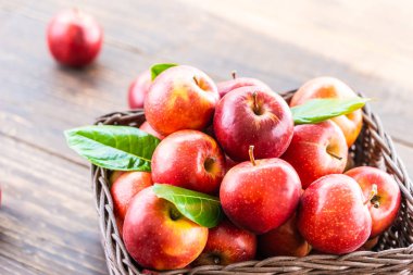 Bir sürü tablo üzerinde kahverengi sepet içinde kırmızı elma meyve