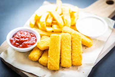 Balık parmak ve patates kızartması veya ahşap kesme tahtası - sağlıksız yiyecek stil üzerinde domates ketçap ve mayonez soslu cips