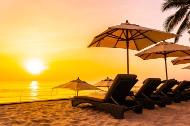 Şemsiye ve şezlong üzerinde güzel plaj ve gündoğumu zaman seyahat ve tatil için deniz
