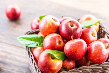 Bir sürü tablo üzerinde kahverengi sepet içinde kırmızı elma meyve