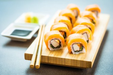 Somon Balık et suşi roll maki wasabi ve soya sosu - Japon yemekleri tarzı ahşap plaka üzerinde