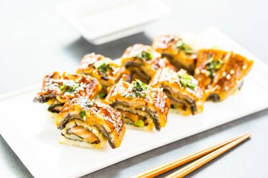 Somon ve beyaz plaka - Japon yemekleri stil üzerinde suşi maki rulo ve tatlı sos içinde sebze ızgara yılan balığı veya unagi balık