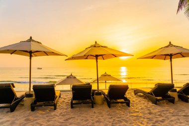 Şemsiye ve şezlong üzerinde güzel plaj ve gündoğumu zaman seyahat ve tatil için deniz