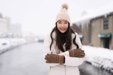 Güzel genç Asyalı kadın gülümseme ve seyahat etmek Otaru kanalında Hokkaido Japonya'da kar ve kış sezonu ile mutlu