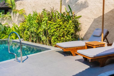 Şemsiye ve boş tatil ve tatil için mavi gökyüzü ve beyaz bulut ile deniz okyanusu plaj yakın yüzme havuzu etrafında sandalye