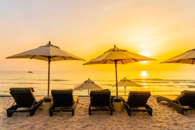 Şemsiye ve şezlong üzerinde güzel plaj ve gündoğumu zaman seyahat ve tatil için deniz