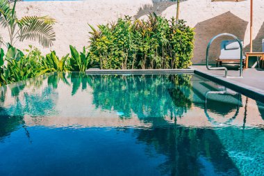 Şemsiye ve boş tatil ve tatil için mavi gökyüzü ve beyaz bulut ile deniz okyanusu plaj yakın yüzme havuzu etrafında sandalye