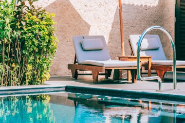 Şemsiye ve boş tatil ve tatil için mavi gökyüzü ve beyaz bulut ile deniz okyanusu plaj yakın yüzme havuzu etrafında sandalye