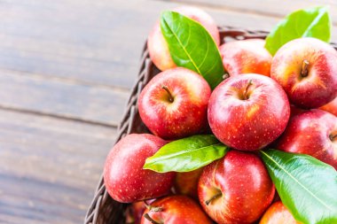 Bir sürü tablo üzerinde kahverengi sepet içinde kırmızı elma meyve