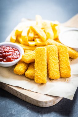 Balık parmak ve patates kızartması veya ahşap kesme tahtası - sağlıksız yiyecek stil üzerinde domates ketçap ve mayonez soslu cips