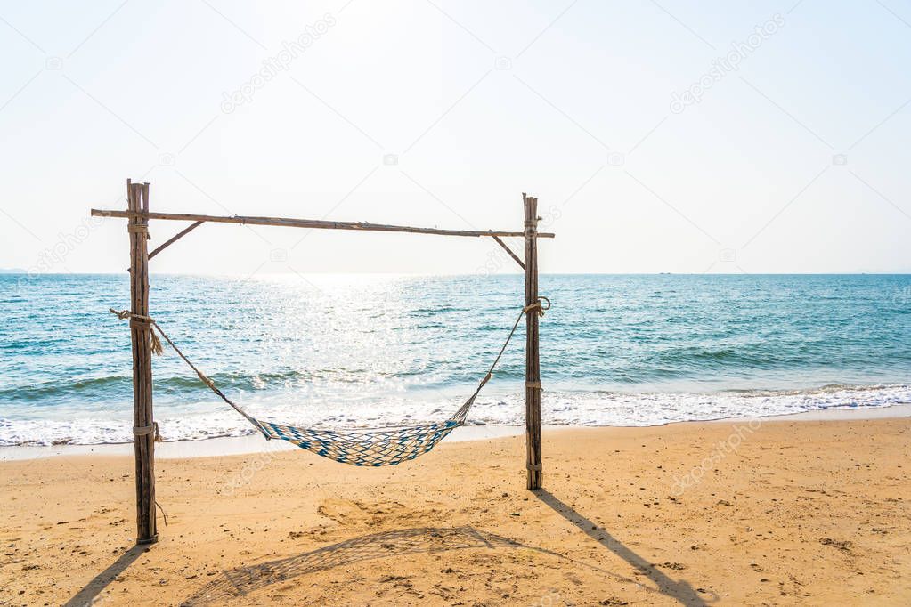 Empty hammock swing on the beautiful beach and sea for holiday vacation travel and leisure concept
