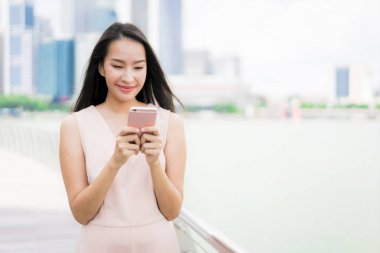Güzel Asyalı kadın konuşmak veya metin için akıllı telefon veya cep telefonu kullanarak