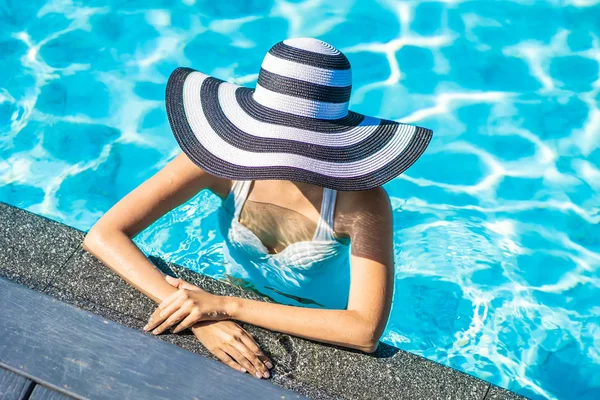 Seyahat ve tatil kavramı için yüzme havuzunda şapkalı güzel genç Asyalı kadın