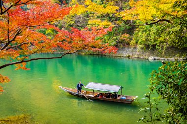 Akçaağaç ağaç yaprak ve etrafında tekne ile güzel Arashiyama Nehri 