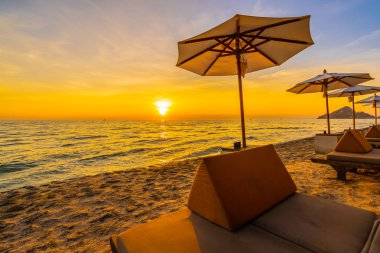 Şemsiye ve plaj ve deniz tatil tatil ve seyahat için gündoğumu veya günbatımı zaman güzel peyzaj etrafında yastık ile sandalye