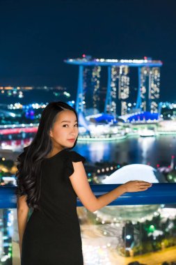 Güzel Asyalı kadınlar gülümseme ve mutlu gece Singapur şehir manzaralı