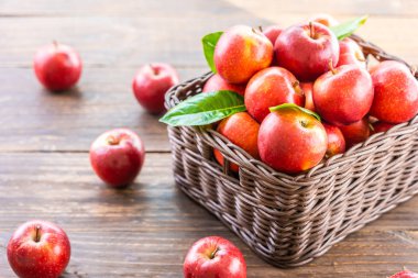 Bir sürü tablo üzerinde kahverengi sepet içinde kırmızı elma meyve