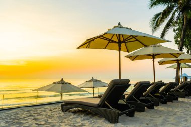 Şemsiye ve şezlong üzerinde güzel plaj ve gündoğumu zaman seyahat ve tatil için deniz