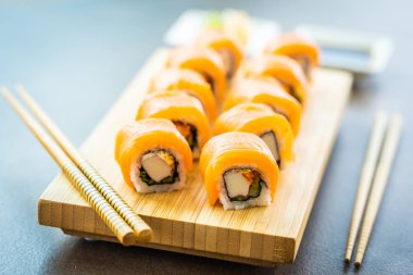 Somon Balık et suşi roll maki ahşap plaka üzerinde
