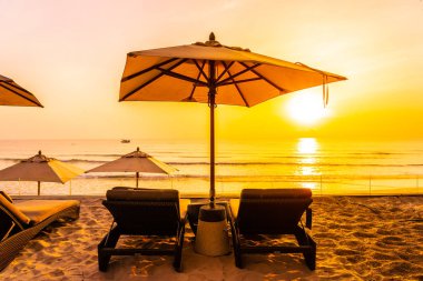 Şemsiye ve şezlong üzerinde güzel plaj ve gündoğumu zaman seyahat ve tatil için deniz