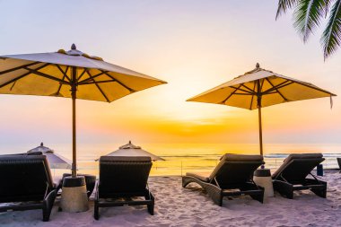 Şemsiye ve şezlong üzerinde güzel plaj ve gündoğumu zaman seyahat ve tatil için deniz