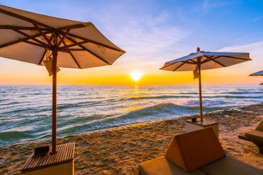 Şemsiye ve plaj ve deniz tatil tatil ve seyahat için gündoğumu veya günbatımı zaman güzel peyzaj etrafında yastık ile sandalye