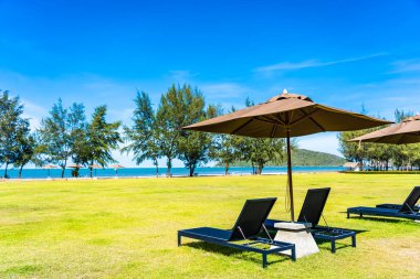 Şemsiye ve yeşil çim sandalye neredeyse deniz plajı ve okyanus boş tatil için