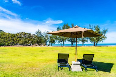 Şemsiye ve yeşil çim sandalye neredeyse deniz plajı ve okyanus boş tatil için
