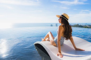Portre güzel genç asyalı kadın gülümseme mutlu eğlence seyahat ve tatil konsepti için otel beldesinde yüzme havuzu etrafında dinlenmek