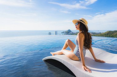 Portre güzel genç asyalı kadın gülümseme mutlu eğlence seyahat ve tatil konsepti için otel beldesinde yüzme havuzu etrafında dinlenmek