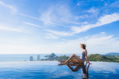 Portre güzel genç asyalı kadın gülümseme mutlu eğlence seyahat ve tatil konsepti için otel beldesinde yüzme havuzu etrafında dinlenmek
