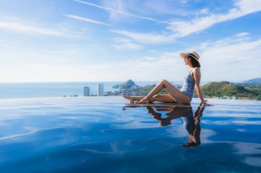 Portre güzel genç asyalı kadın gülümseme mutlu eğlence seyahat ve tatil konsepti için otel beldesinde yüzme havuzu etrafında dinlenmek