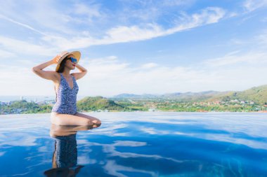 Portre güzel genç asyalı kadın gülümseme mutlu eğlence seyahat ve tatil konsepti için otel beldesinde yüzme havuzu etrafında dinlenmek