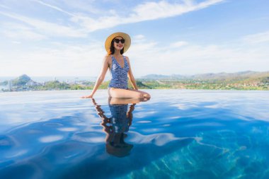 Portre güzel genç asyalı kadın gülümseme mutlu eğlence seyahat ve tatil konsepti için otel beldesinde yüzme havuzu etrafında dinlenmek