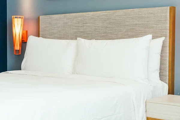Роскошная удобная подушка на кровати с легким лампом — стоковое фото