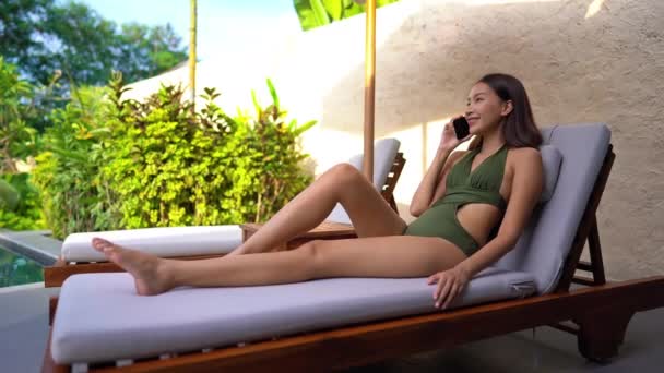 美丽的亚洲年轻女子在池畔通过电话交谈的镜头 — 图库视频影像