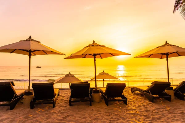 Guarda-chuva e cadeira na bela praia e mar ao nascer do sol tim — Fotografia de Stock