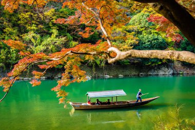 Akçaağaç ağaç yaprak ve etrafında tekne ile güzel Arashiyama Nehri 
